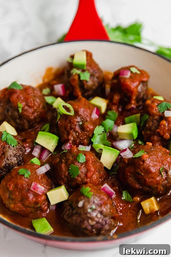 A pan filled with cooked enchilada skillet topped with avocado and fresh herbs.