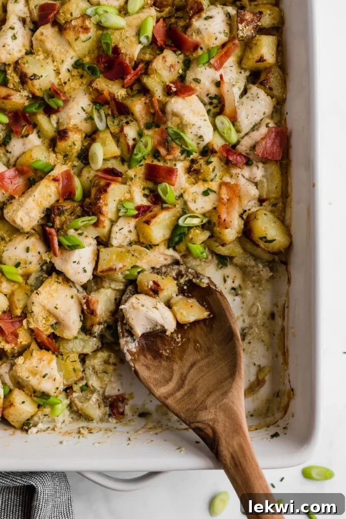 A large baking dish brimming with freshly cooked chicken bacon ranch casserole, a wooden spoon scooping out a generous portion, emphasizing its readiness and deliciousness.