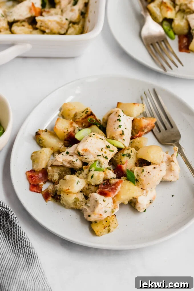 A single serving of chicken bacon ranch casserole arranged beautifully on a white plate, with a fork beside it, inviting the viewer to enjoy its deliciousness.
