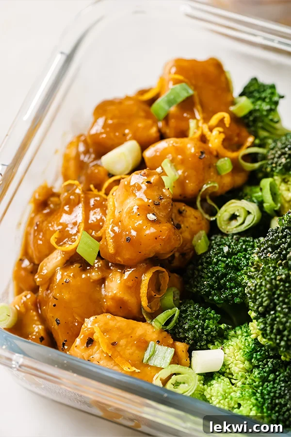 Broccoli with orange chicken in a glass container.
