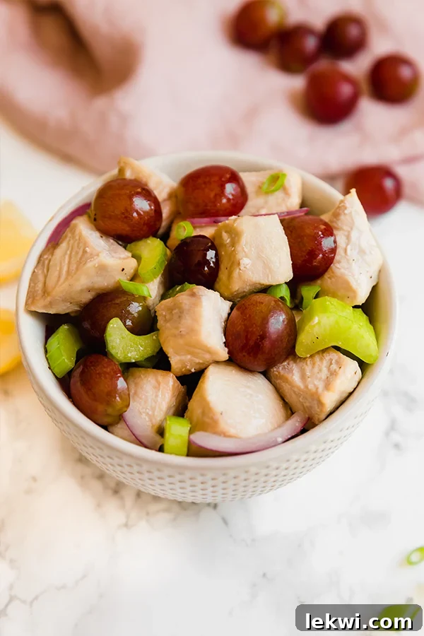 A vibrant bowl of healthy, no-mayo chicken salad with fresh ingredients, garnished with green onions.
