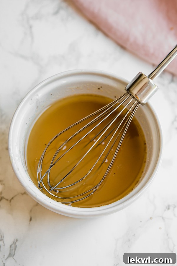 A close-up of the light and zesty olive oil and vinegar dressing being prepared for a healthy chicken salad.