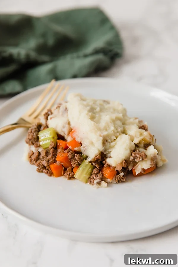 A perfectly portioned serving of delicious cauliflower shepherd's pie resting on a plate, with a fork invitingly placed beside it.