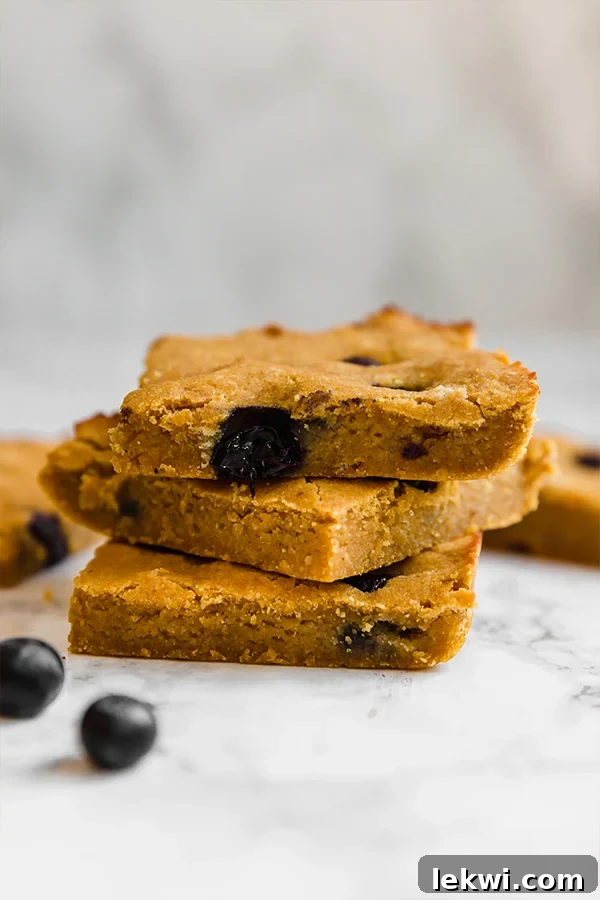A beautifully arranged stack of wholesome pumpkin blueberry breakfast bars, adorned with fresh blueberries, ready for a nutritious start to the day.