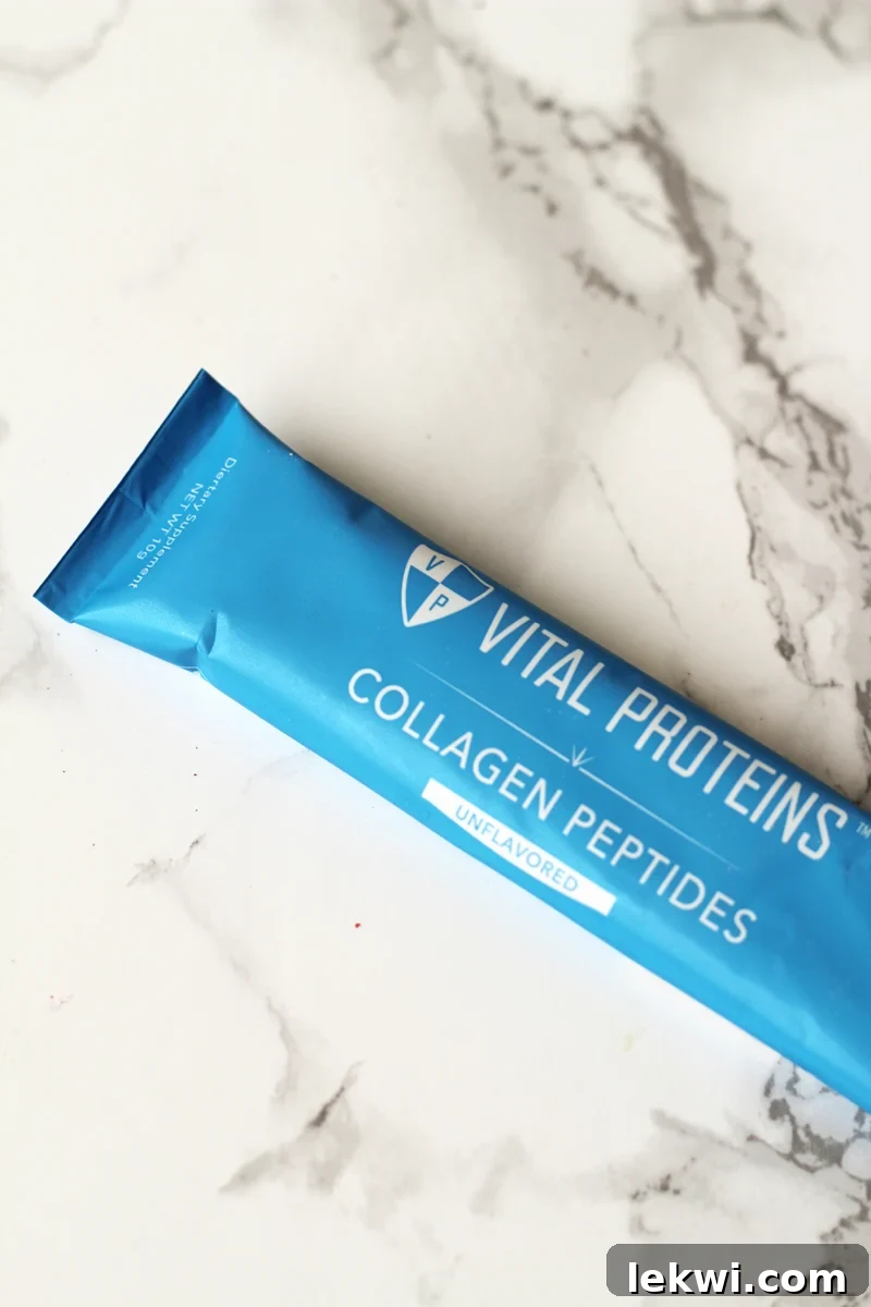 A single serve packet of collagen on a white marble background.