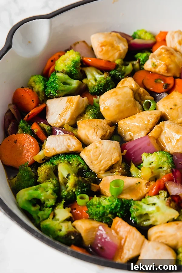 A close-up view of the teriyaki chicken stir-fry cooking in a skillet, showcasing the rich sauce clinging to the chicken and crisp vegetables.