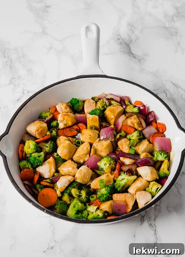 A close-up image of the finished teriyaki chicken stir-fry in a serving bowl, garnished with fresh green onions, highlighting its appetizing texture and vibrant colors.