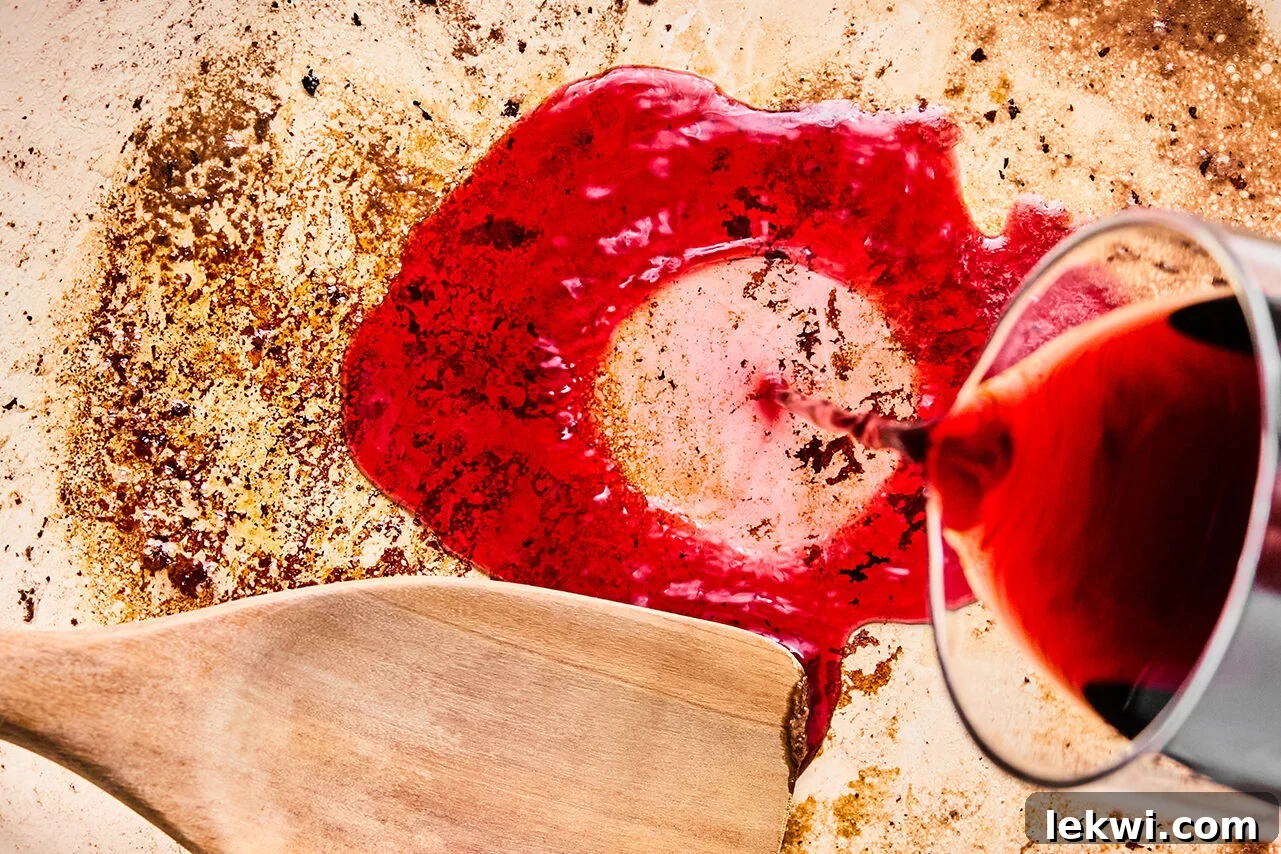 Wine being poured over a skillet to deglaze the pan.