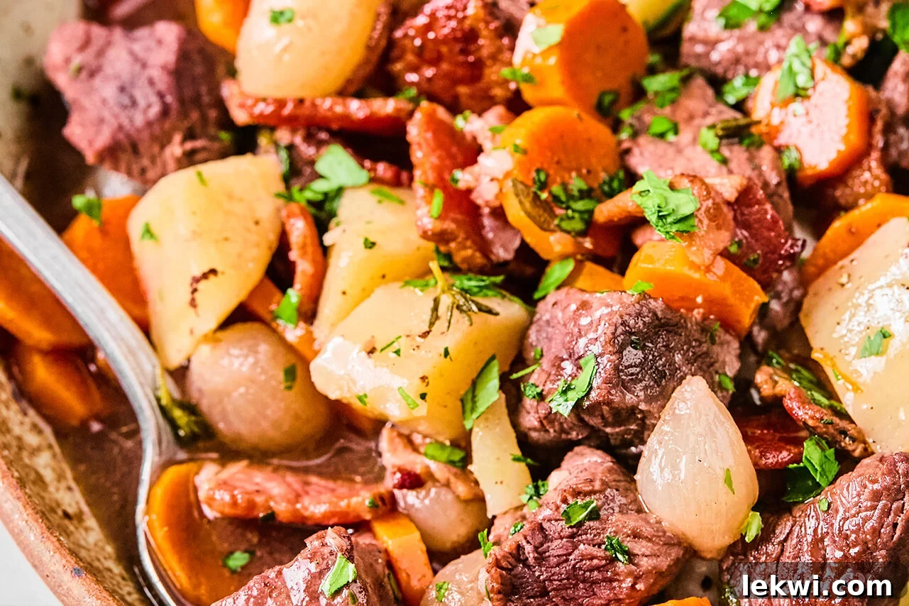 Slow cooker beef bourguignon in a large bowl with a spoon.