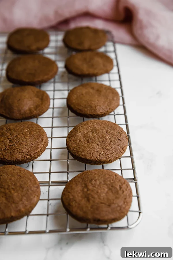 Freshly baked homemade Paleo Oreo cookies cooling on a wire rack, showcasing their dark color and delicate texture.