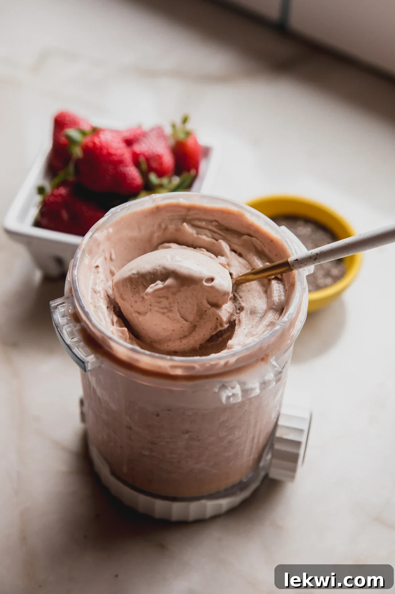 A ninja creami pint container of chia seed ice cream after spinning with a spoon taking a spoonful out.