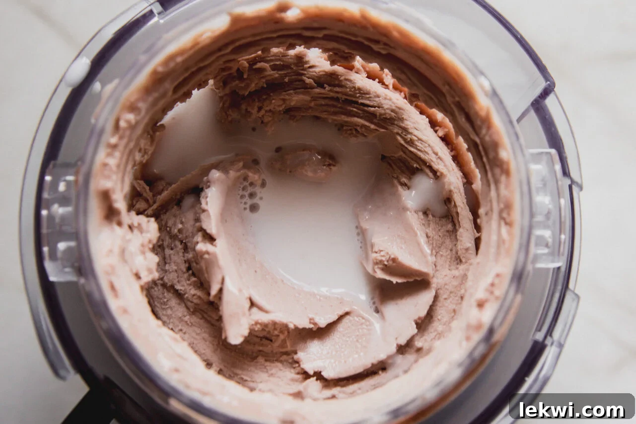 The creami container after one mixing with a well in the middle with almond milk poured in.
