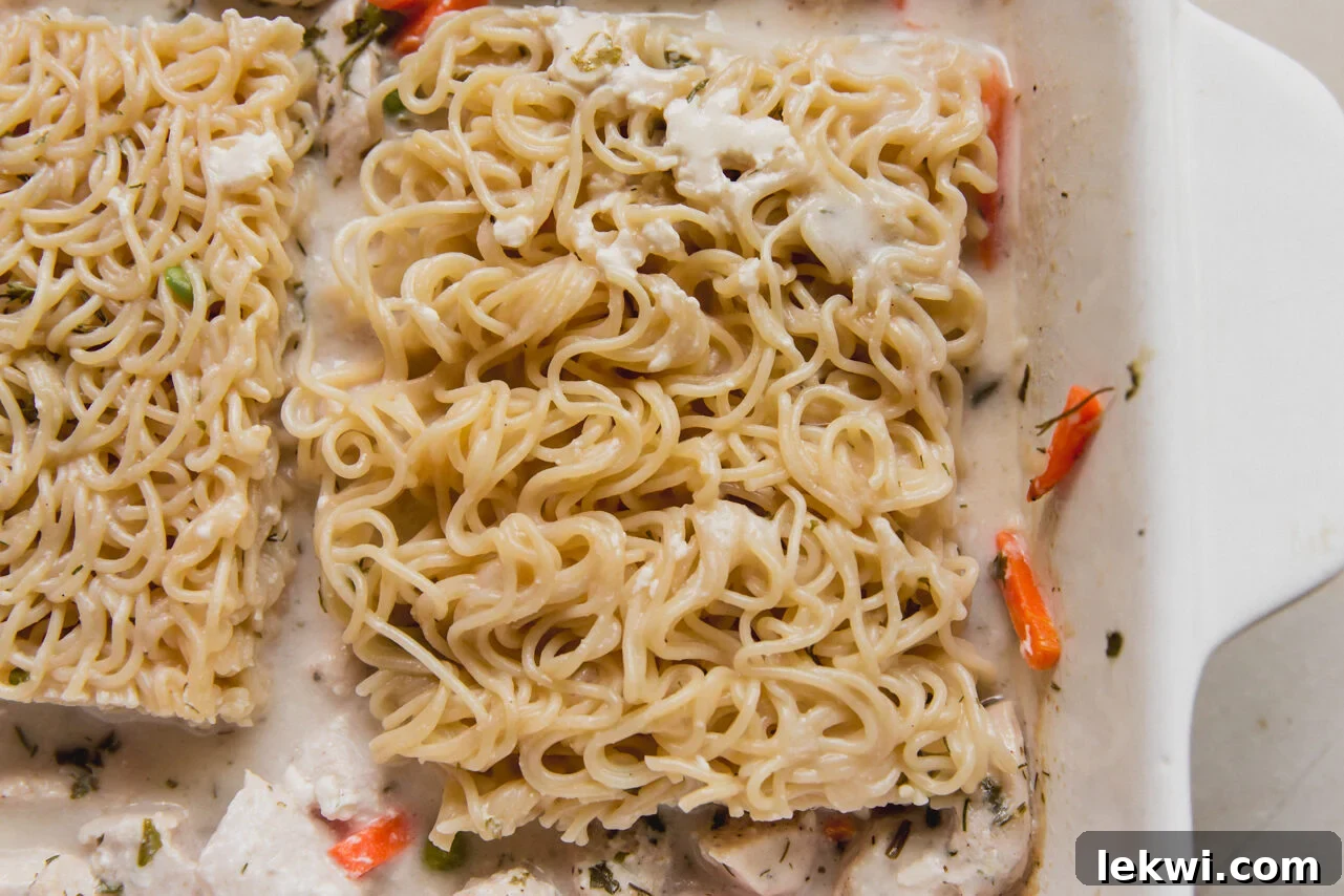 The casserole dish now contains the ramen, chicken, and vegetables, with a mixture of chicken broth and arrowroot starch being poured over them.