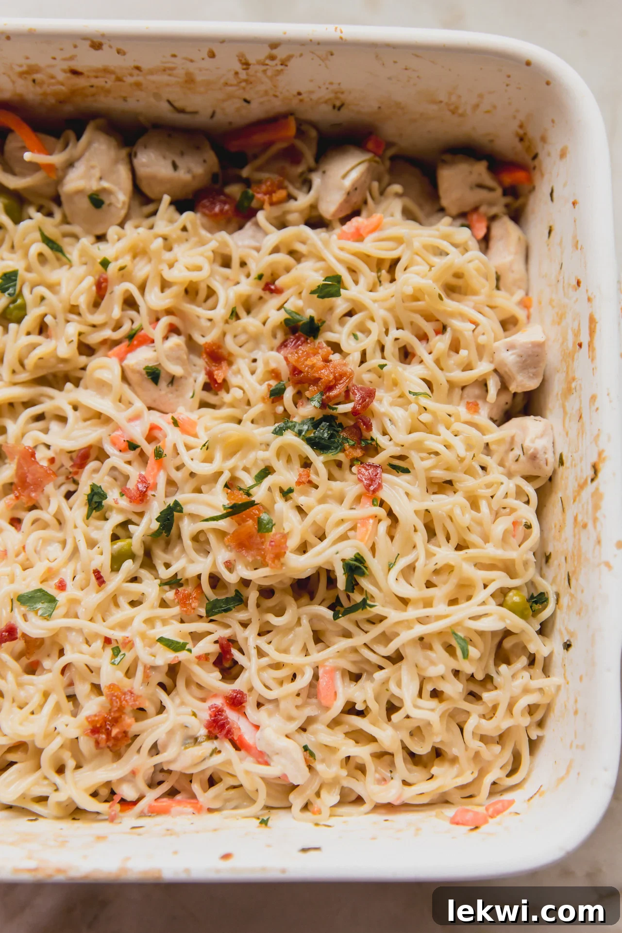 A wide shot of the Bacon Ranch Ramen Bake in a large rectangular casserole dish, garnished with parsley and bacon, fresh from the oven.