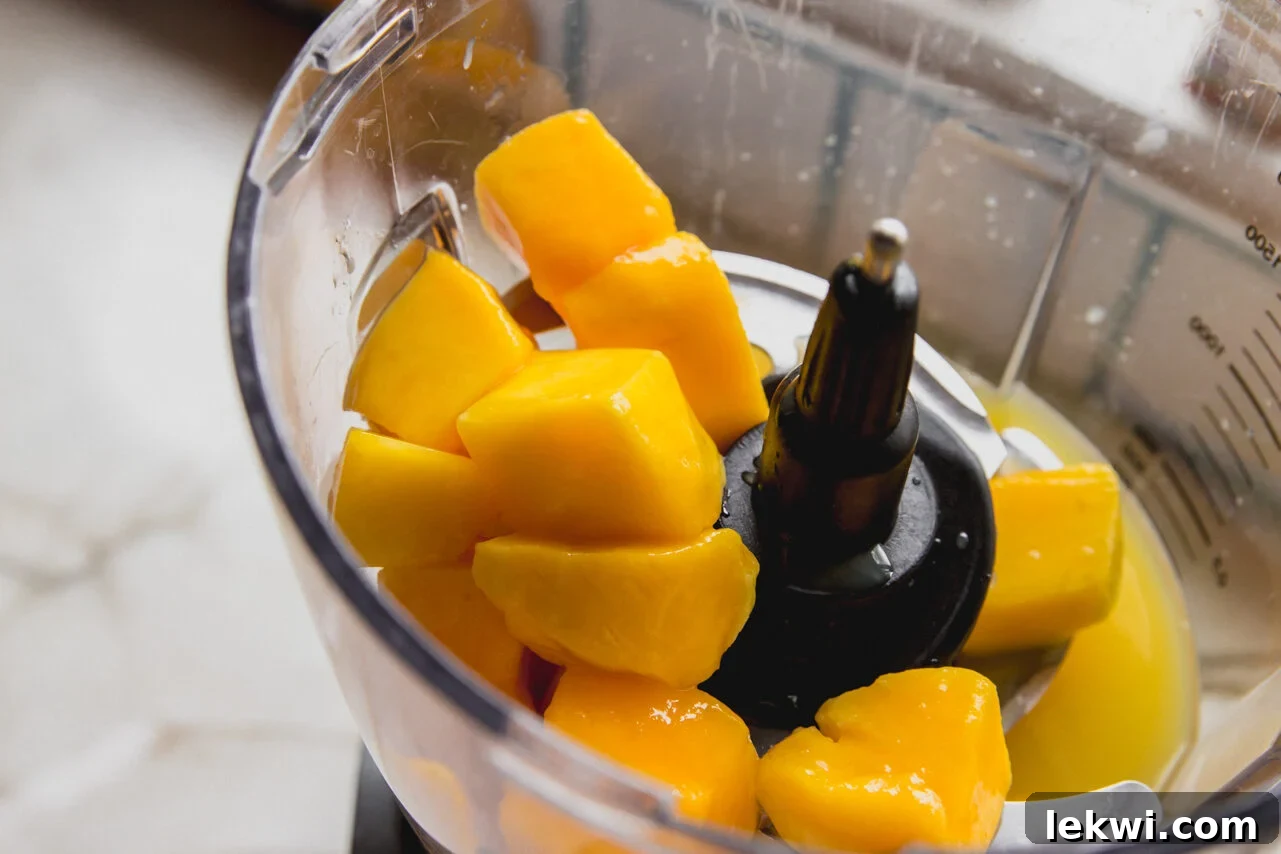 Chewy Matcha Mango Delights 5 A food processor with mango and orange juice before blending.