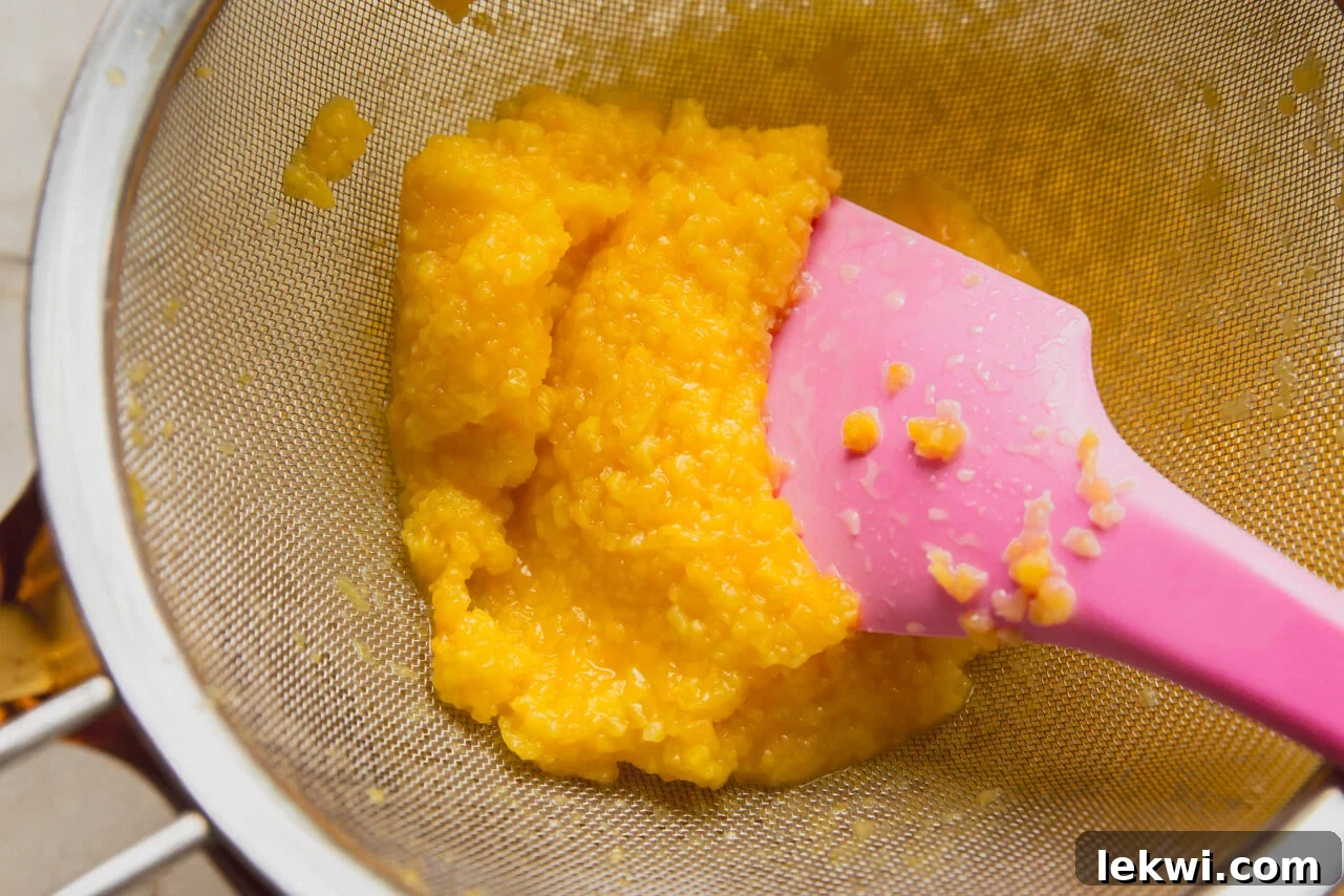 Chewy Matcha Mango Delights 6 A spatula pushing down the mango orange juice mixture to seperate the pulp and juice.