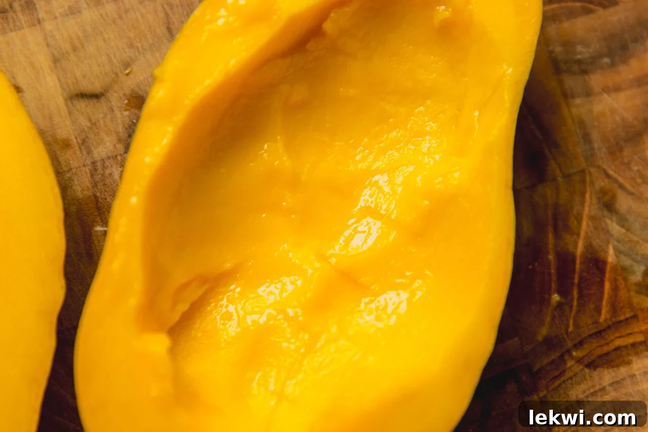 Tropical Mango Coconut Posset 4 A hollowed out mango half sitting on a wooden cutting board, ready to be filled.