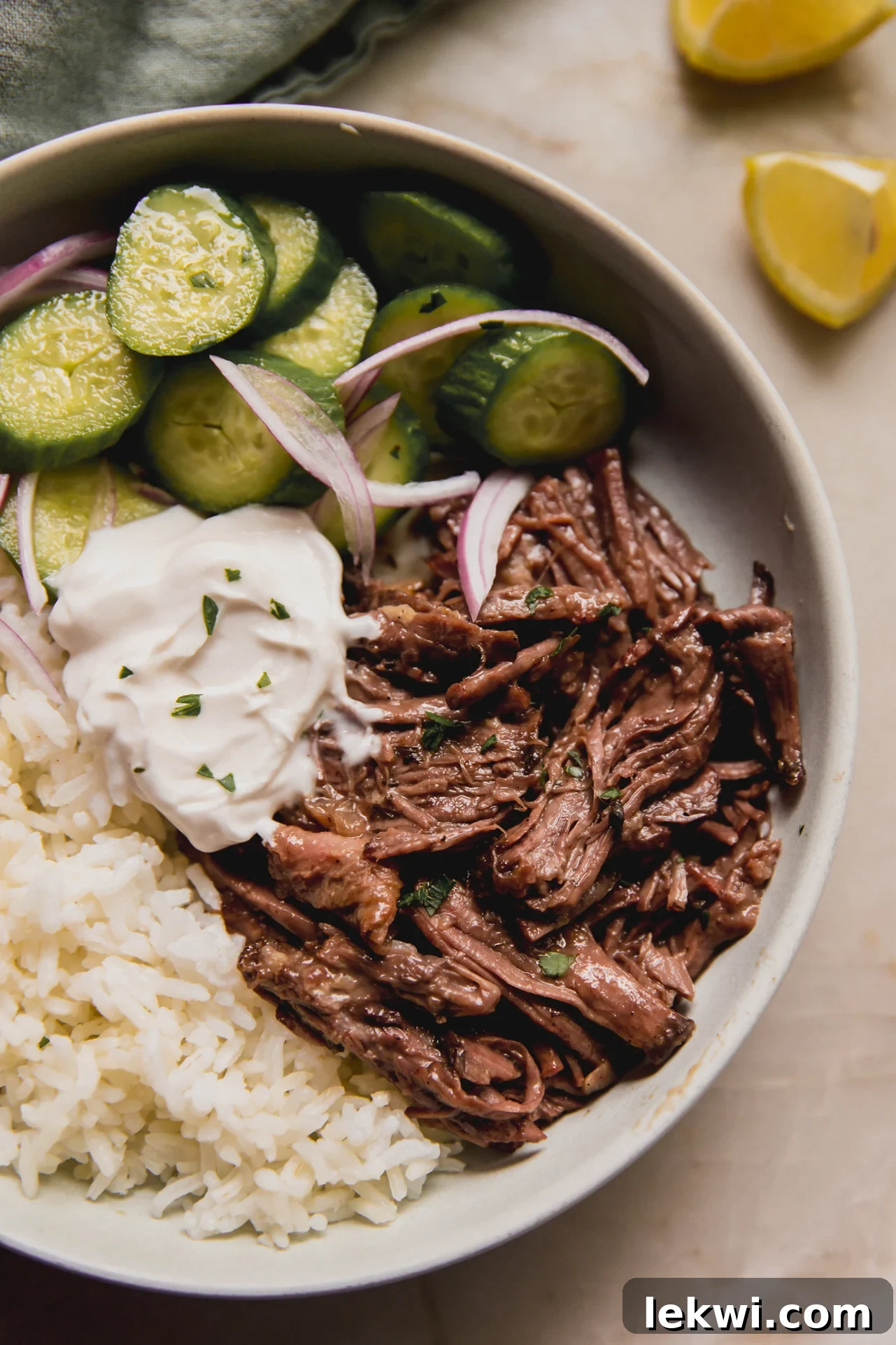 Mediterranean pot roast in a bowl with rice, dairy-free tzatziki, and a cucumber salad on the side.