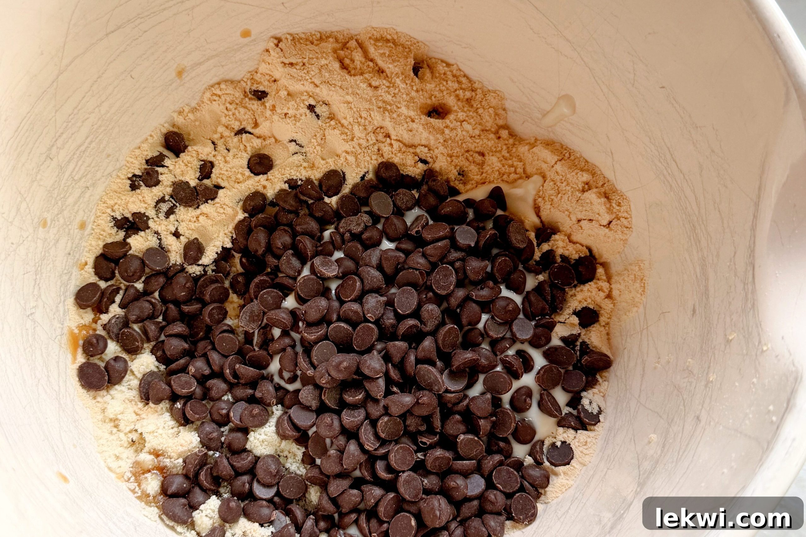 Ingredients for protein cookie dough in a white bowl before mixing.