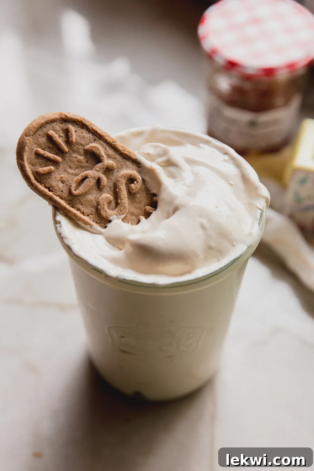 A glass cup of peach vanilla marshmallow fluff topped with a crispy Biscoff cookie for dipping.