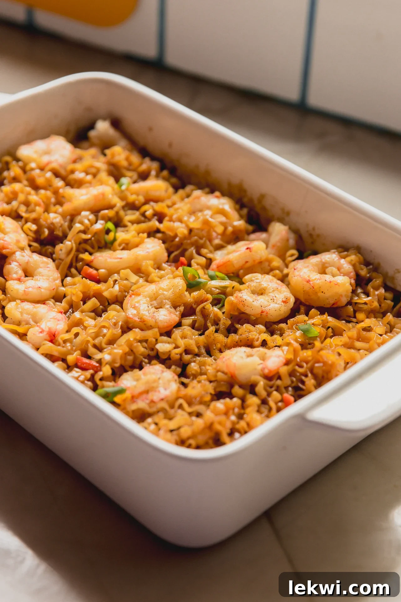 Cooked shrimp and ramen in a large white glass baking dish.