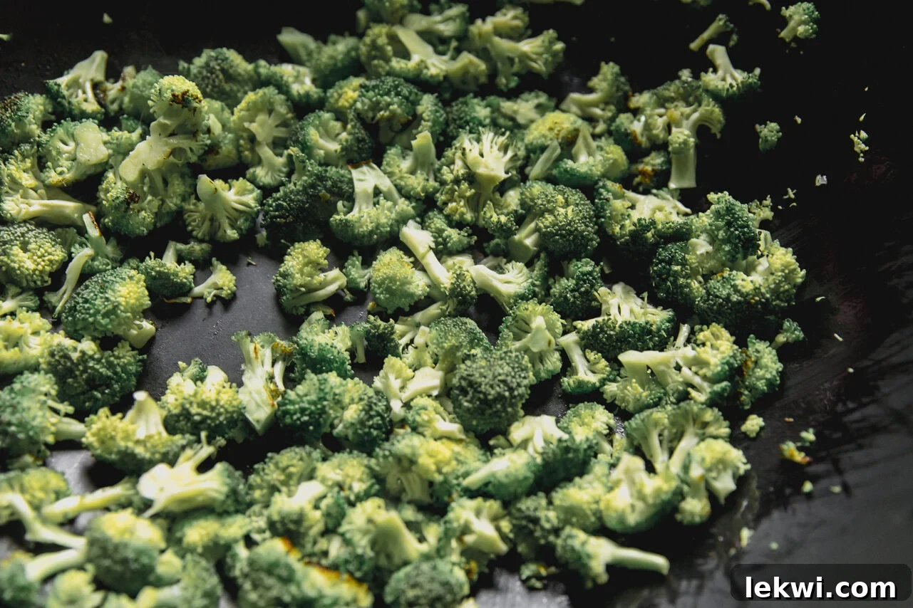A wok with broccoli sauting in it.