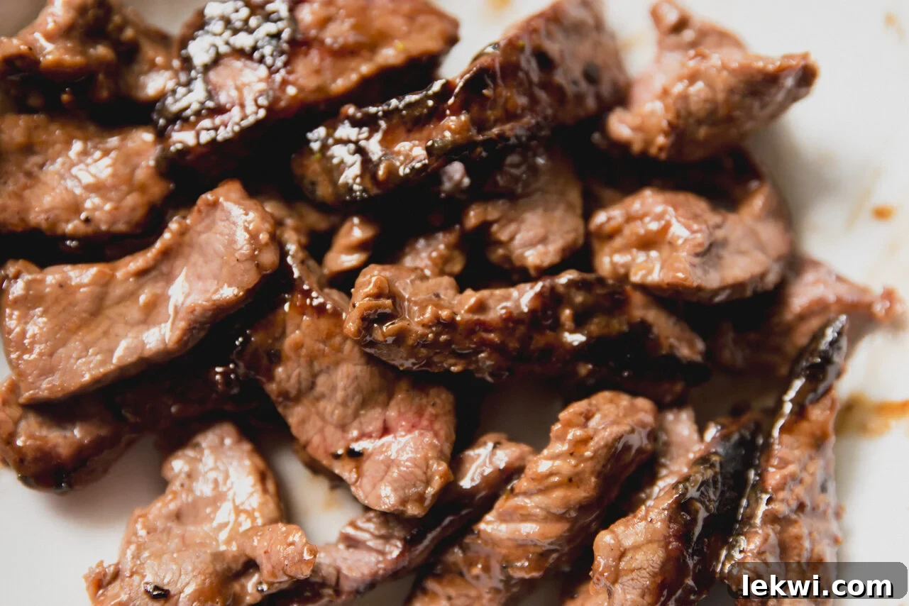 A white plate with cooked sirloin steak on it.