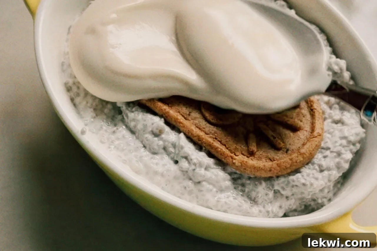 Gluten-Free Protein Tiramisu Recipe: High-Protein Dessert Without Gluten 7 A ramekin filled with chia seed mixture with a breakfast biscuit on top and a spoon adding yogurt over the top.