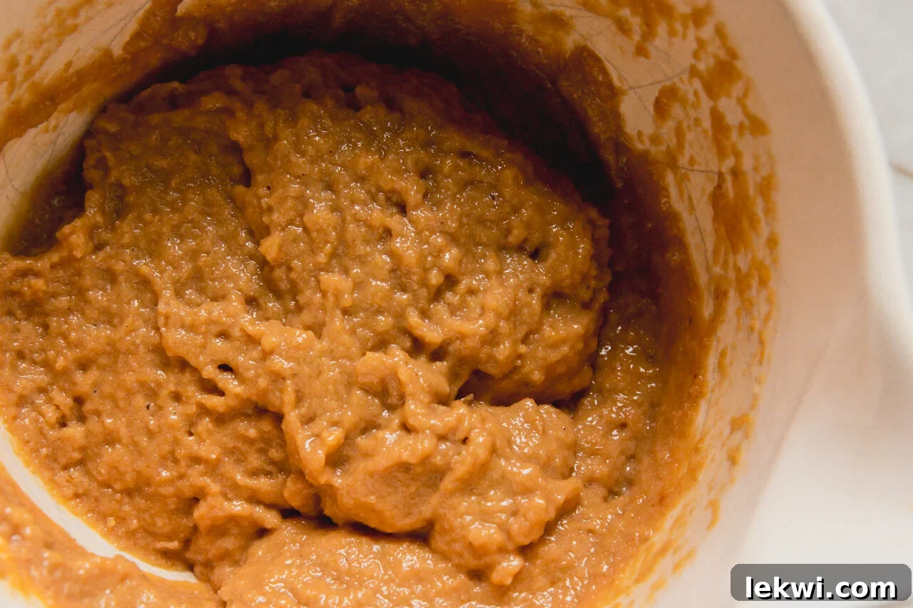 A white ceramic bowl filled with batter to make high protein muffins.